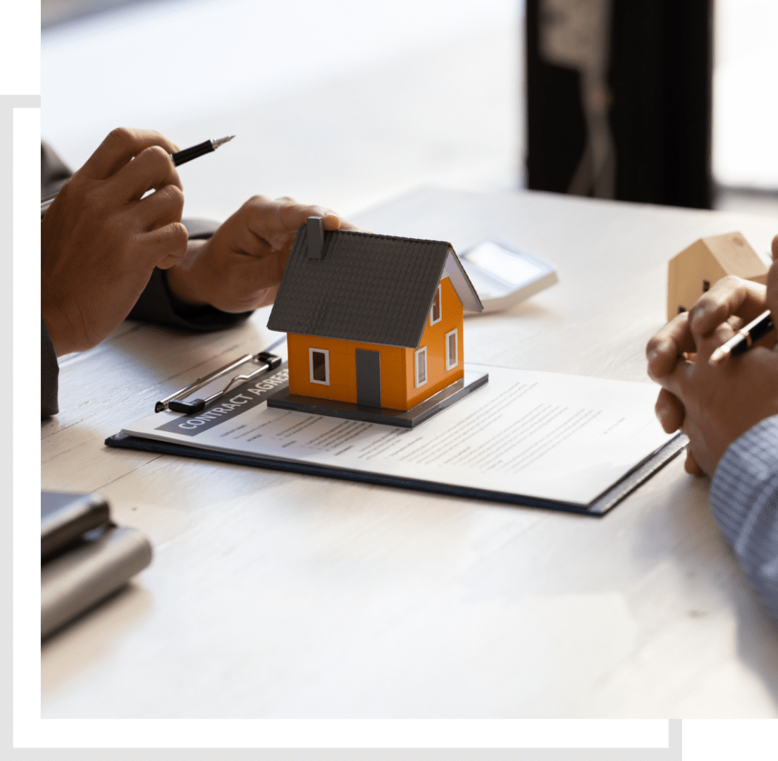Two people are sitting at a table with a model house.